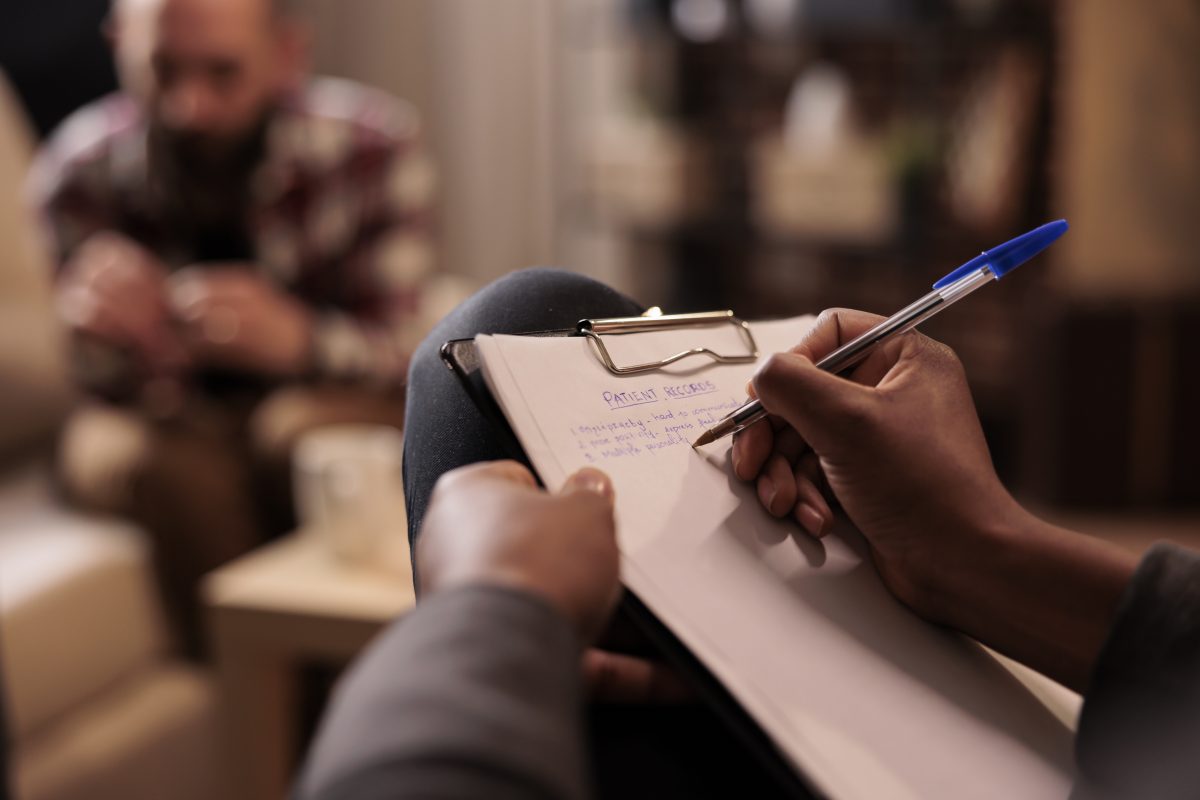 Clinician documenting psychometric assessment findings on a patient record
