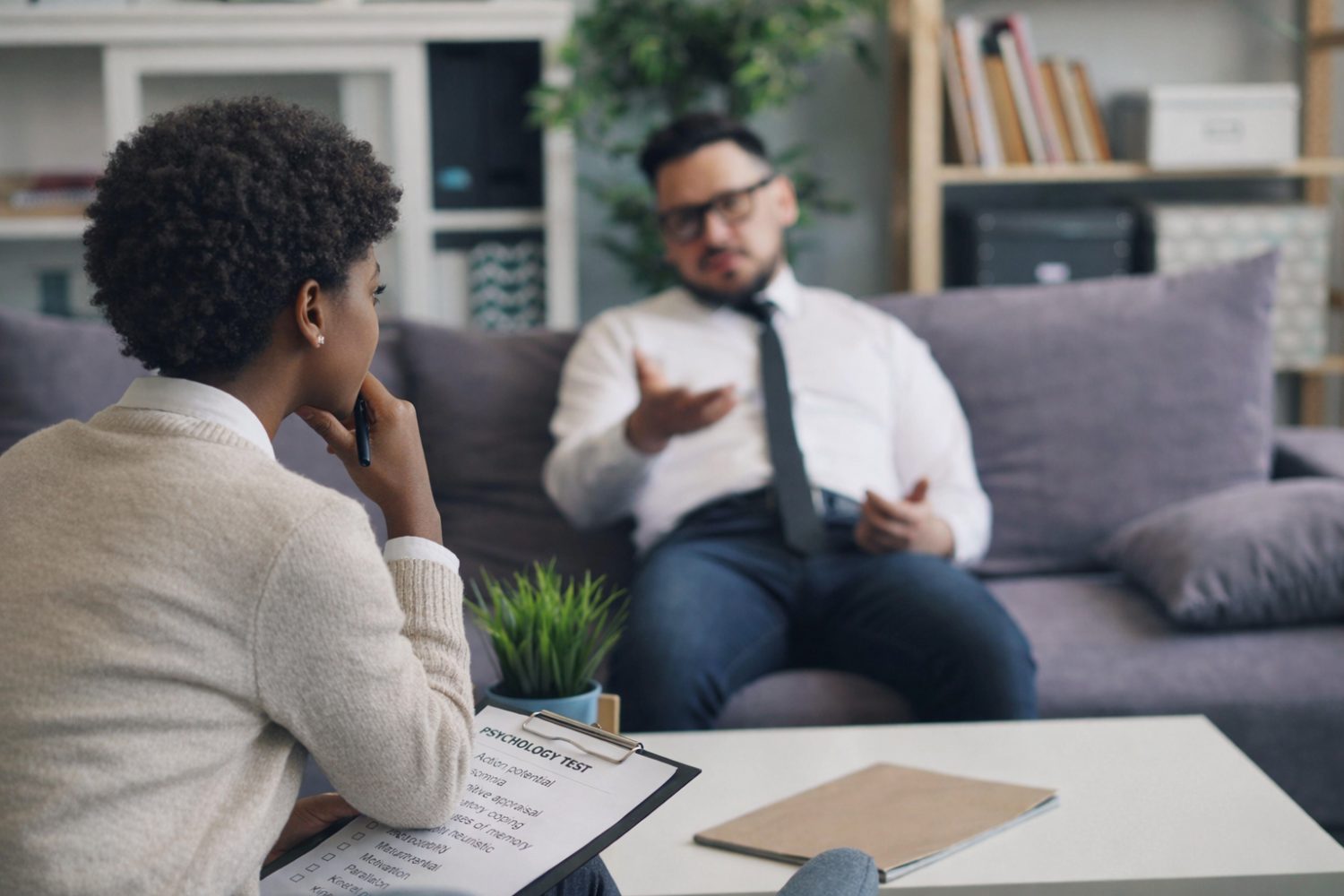 Psychologist recording responses on a psychological test form while a client speaks